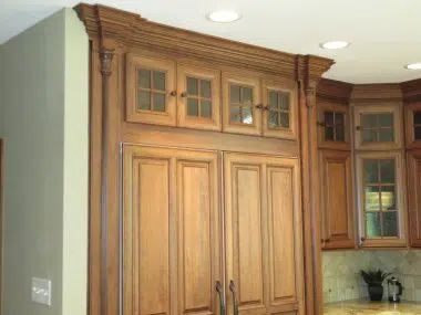 Paneled refrigerator and freezer with lighted cabinets over top and onlays on each end