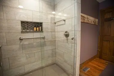 Beautiful walk-in shower with glass doors and brick pattern tile in the cut out shelf