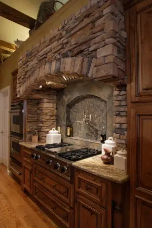 This stone hearth is the heart of this kitchen with rustic alder cabinetry flanking the sides 