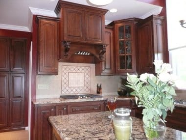 Decorative wood range hood with cobble and deco tile below 