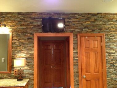 Mounted TV above doorway with floor to ceiling tile work 