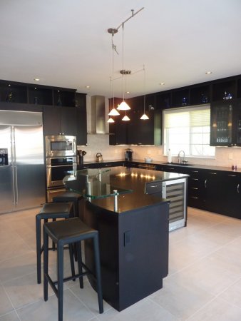 Contemporary black kitchen with curved pendent lighting and curved glass bar top