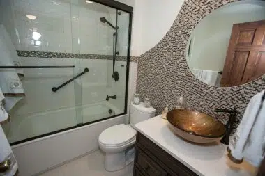 Traditional guest bathroom with beautiful tile accents and glass door to shower/tub combination