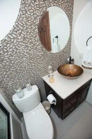 The sweeping accent tiles off sets the round mirror and vessel bowl