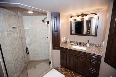 Large corner shower with floor to ceiling tiles and onyx shower base with cherry cabinetry 