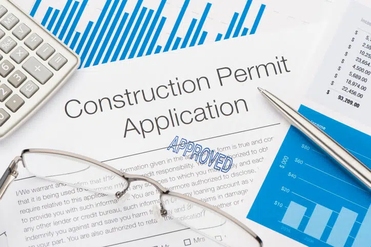 Approved Construction Permit Application with pen and calculator